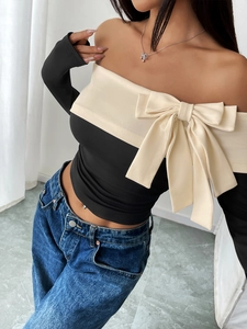Detail of off-shoulder long sleeve top with a large decorative bow and contrast colors