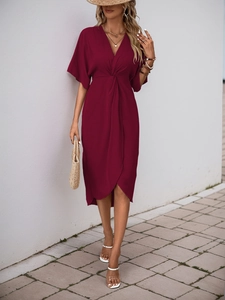 Detail of burgundy deep V-neck dress with twist-front waist and irregular tulip hem