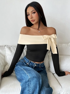 Detail of off-shoulder top with contrast fold and elegant bow decoration on chest