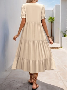 Detail of beige tiered midi dress featuring short puff sleeves and multi-layer skirt