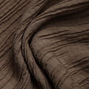 Dettaglio del tessuto marrone caffè con texture ondulata 3D per pantaloni estivi casual