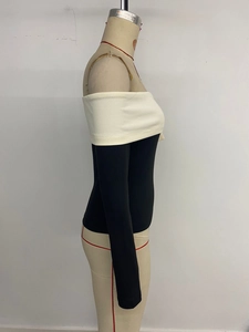 Detail of off-the-shoulder neckline with cream trim and black long-sleeve knit fabric