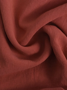 Macro texture of pleated terracotta fabric showing soft drapery and woven texture