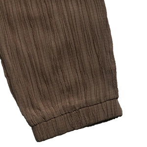 Dettaglio macro dei pantaloni marroni scuri in tessuto increspato con polsini elastici