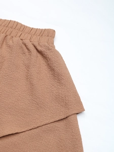 Close-up of caramel textured fabric showing elastic waistband and ruffled hem details