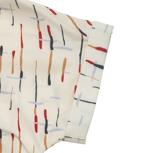 Detailed close-up of rolled sleeves on a cream shirt with modern abstract line patterns