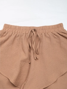 Detailed view of brown textured fabric with elastic waistband and ruffle layering