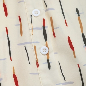 Close-up of beige shirt featuring abstract colored stripes and white four-hole buttons