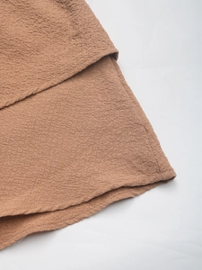 Detail shot of the ruffled hem and textured seersucker fabric of brown casual shorts
