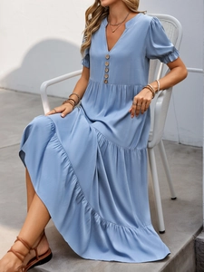 Detail of light blue tiered dress featuring V-neckline with decorative buttons and ruffle sleeves