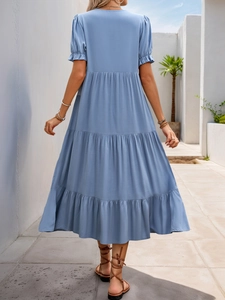 Back view of a light blue layered maxi dress featuring puff sleeves and tiered skirt details