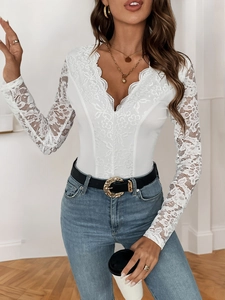 Detail of the plunging V-neckline and intricate floral lace trim on white bodysuit