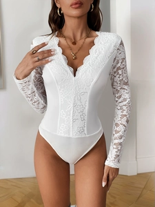 Close-up of intricate floral lace trim and deep V-neckline on a white long sleeve bodysuit