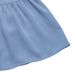 Macro shot of light blue twill fabric showing ruffled hem and precise stitching detail
