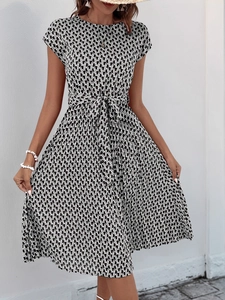 Detail of black and white geometric print dress featuring a tied waist and pleated hemline
