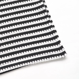 Macro detail of black and white striped knit fabric with wavy texture and seamless hem