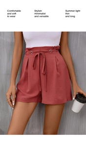 Macro detail of high-waist brick red shorts featuring a paperbag waist and tie belt