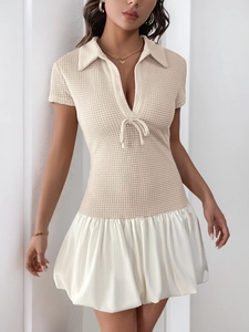 Detailed close-up of beige waffle knit bodice with V-neck and white pleated satin skirt