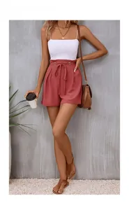 Detail of high-waisted brick red shorts with ruffled waist and stylish matching tie-belt