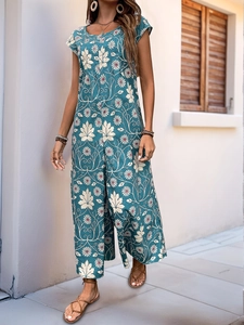 Detail of teal summer jumpsuit with white floral patterns and bohemian loose-fit leg design