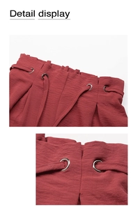 Detail of red paperbag waist shorts with metal eyelets and textured fabric tie belt