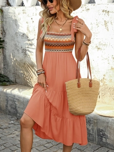 Detail of bohemian coral orange tiered dress with adjustable bow straps and geometric patterns