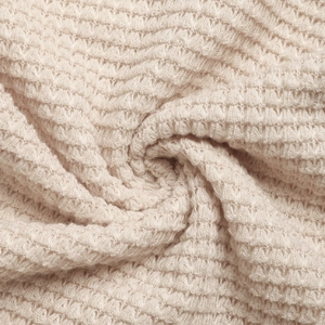 Macro view of light beige waffle knit fabric with soft textured honeycomb pattern weave