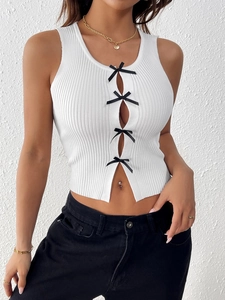 Détail du haut court en tricot côtelé blanc avec nœuds noirs et motif ajouré élégant