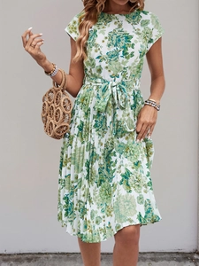 Detail of summer dress featuring green floral print with a waist tie and pleated skirt