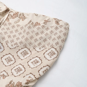 Close-up of ethnic floral print on beige fabric for a bohemian sleeveless jumpsuit
