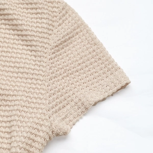 Detailed close-up of beige waffle knit texture on the sleeve of a women's dress