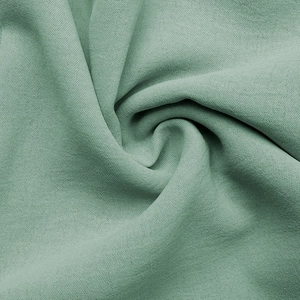 Macro shot of sage green cotton linen fabric showing the woven texture and soft drape