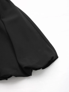 Detailed view of the smooth black fabric texture and soft drapes on this summer dress