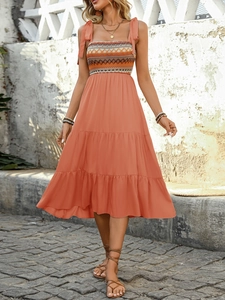 Detailed view of bohemian floral dress with smocked bodice and woven geometric patterns