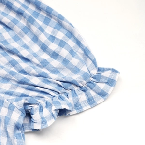 Close-up of blue gingham fabric with pleated ruffles and textured cotton-linen weave