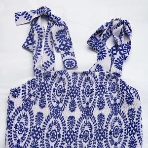 Detail of tie-shoulder straps and smocked bodice on blue floral summer dress