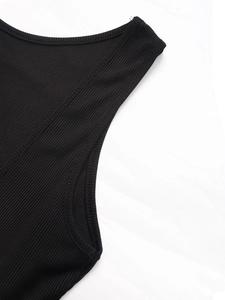 Close-up of black ribbed fabric showing fine stitching and vertical knit texture on a mini dress