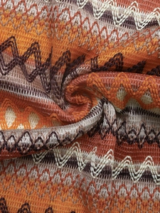 Close-up of the knitted zigzag pattern and textured woven fabric in warm earth tones