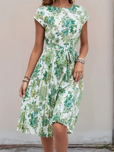 Detail of summer dress featuring green geometric print and waist tie on white fabric