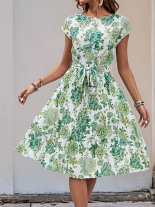 Detail of summer dress featuring pleated skirt with green floral print and waist belt