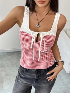 Detail of red gingham crop top featuring white ruffled trim and front bow tie design