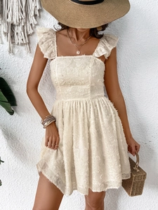 Detail of off-white summer dress featuring textured floral fabric and ruffle shoulder straps