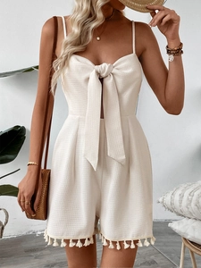 Detail of waffle textured romper featuring oversized bow tie and tassel hem details