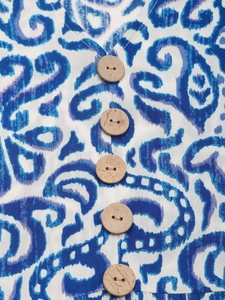 Detail of V-neck print dress with blue paisley pattern and natural wood buttons