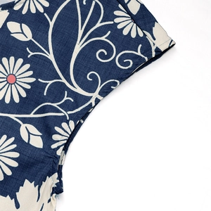 Detail shot of navy blue jumpsuit fabric featuring white daisy floral prints and stitching