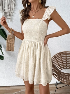Close-up of white mini dress featuring textured fringe fabric and ruffle shoulder straps