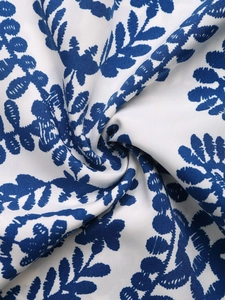 Détail du tissu à fleurs avec un drapé souple et des motifs de feuilles bleues