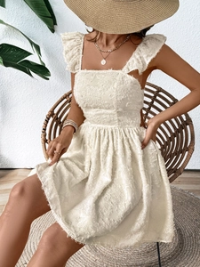 Close-up of white dress showing textured fabric and elegant ruffle straps detail