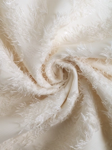 Detail shot of the cream flutter sleeve dress showing textured fringe fabric craftsmanship