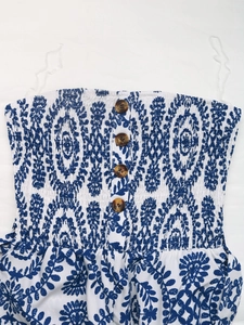 Vue détaillée du tissu fleuri bleu smocké avec boutons décoratifs en résine ambre